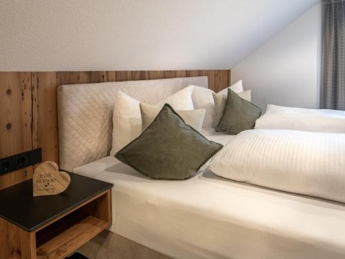 a bedroom with a large white bed with pillows at Mäsers Allgäuherz in Wiggensbach