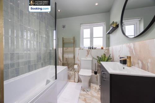 a bathroom with a tub and a toilet and a sink at Luxuriou 5 Bedroom House By Homebird Property Management Short Lets & Serviced Accommodation Leeds With Private Parking & Free WiFi in Leeds