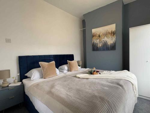 a bedroom with a large bed with a blue headboard at Wallasey Home - 2 Min to Liverpool Ferry Seacombe, Beach & Free Parking in Wallasey
