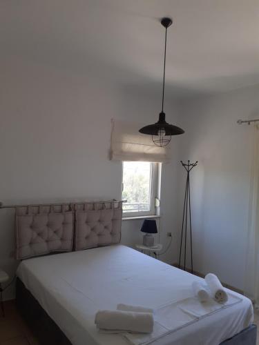 Un dormitorio con una cama con sábanas blancas y una ventana. en Villa Thea, en Sísion