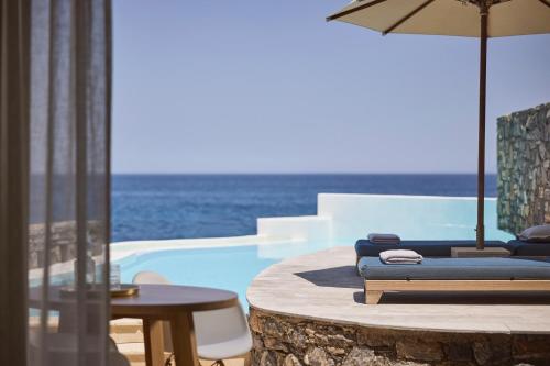 a pool with chairs and a table and an umbrella at St. Nicolas Bay Resort Hotel & Villas in Agios Nikolaos