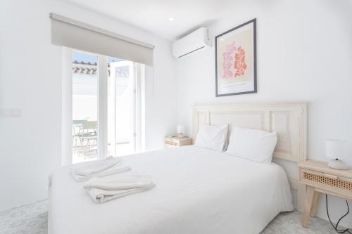 a white bedroom with a white bed and a window at Alma Marina Lagos in Lagos