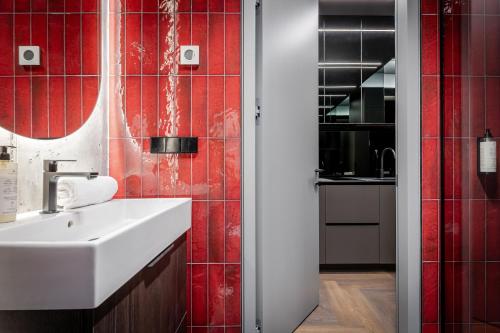a bathroom with a white sink and red tiles at 69 Fetish Apartments with Free Underground Parking in Kaunas