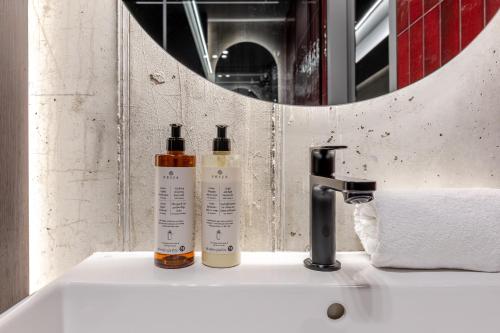two bottles ofodorizers sitting on a sink in a bathroom at 69 Fetish Apartments with Free Underground Parking in Kaunas