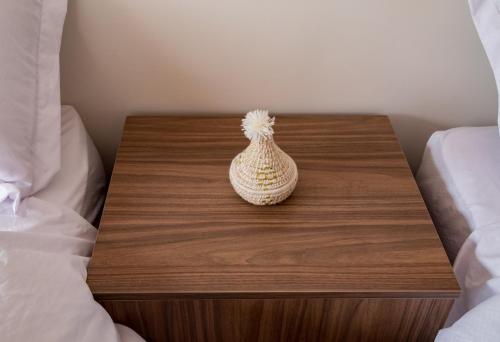 a small vase sitting on a wooden table next to a bed at Appartement Dar Tamraght in Tamraght Ouzdar