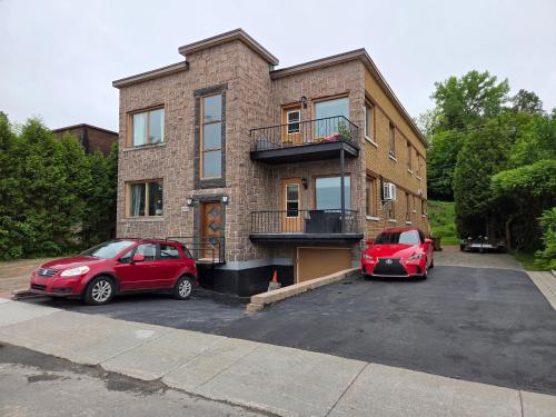 two cars parked in a parking lot in front of a building at Chambre chez Martin in Saguenay