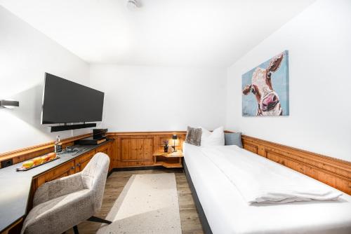 a hotel room with a bed and a tv at Mäsers Allgäuherz in Wiggensbach
