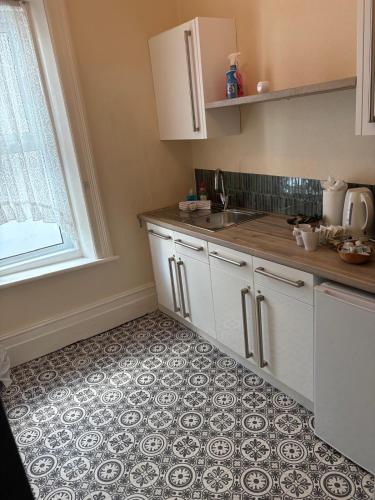 a kitchen with white cabinets and a tile floor at Bronte House - Blackpool in Blackpool