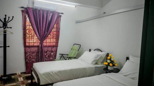 a bedroom with two beds and a window with purple curtains at Homestay Kuala Lumpur in Kuala Lumpur