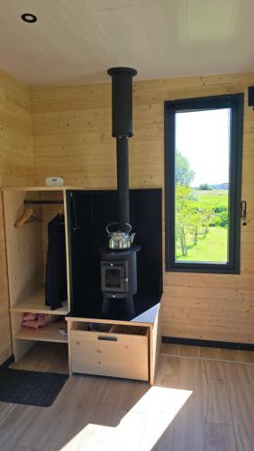 a woodburning stove in a room with a window at La cachette du Jura in Bois-dʼAmont