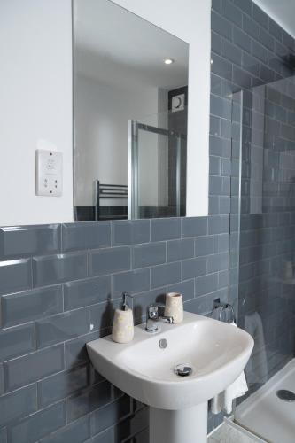 a blue tiled bathroom with a sink and a mirror at Fox ford 51 in Seaton