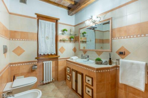 un bagno con lavandino, WC e specchio di Villa Soli - Casa in Pietra con Piscina Panoramica a Sassorosso