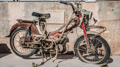 an old motorcycle parked in front of a wall at Viles Can Moreno in Ses Salines
