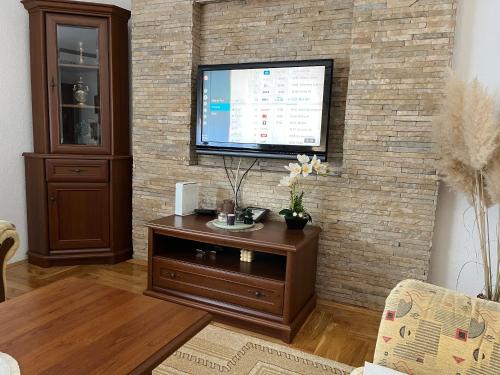 a living room with a television on a brick wall at Luxury Apartment in Mladenovac