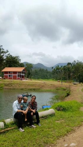 a group of three men sitting next to a body of water at Nature Spot Cottages Coorg in Kurchi