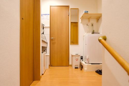 a hallway with a wooden door and a refrigerator at Ueno Hoshi-5 minutes from Iriya Station-1 stop from Ueno station in Tokyo