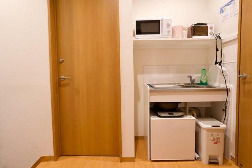 a door to a kitchen with a microwave and a counter at Ueno Hoshi-5 minutes from Iriya Station-1 stop from Ueno station in Tokyo