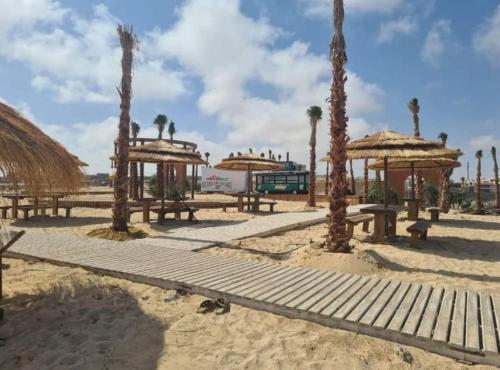 a group of picnic tables and umbrellas on the beach at GAIA North coast Ras El Hekma in Banī Ghālib