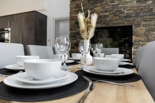 a dining room table with white dishes and wine glasses at Devon Hot Tub Retreat in Bideford
