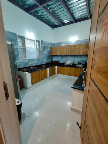 a large kitchen with a white floor and wooden cabinets at Tropica Retreat by Dazzle Destinations - Private Waterfalls, Private Rooms and Bonfire in Aldūr
