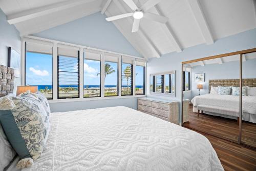 Schlafzimmer mit einem Bett und Fenstern mit Meerblick in der Unterkunft Makanui 221 in Kipu