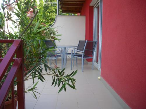 a patio with a table and chairs on a red wall at House Hévíz in Hévíz