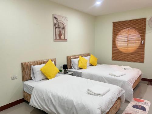two beds with yellow pillows in a room at Muttafa House in Nai Yang Beach