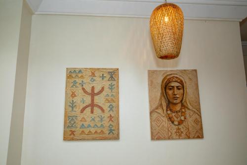 two pictures of a woman on a wall with a lamp at Appartement Dar Tamraght in Tamraght Ouzdar