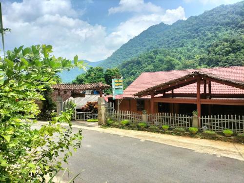 a building with a fence in front of a mountain at Nam Pé Tày Homestay - View hồ Ba Bể in Bak Kan