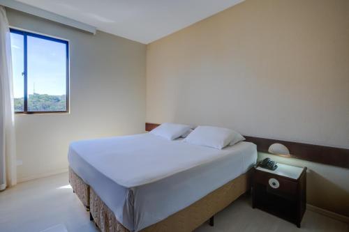 a bedroom with a large bed with a window at Slaviero Londrina Flat in Londrina