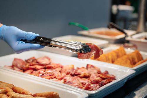Iemand legt spek in een schaal met eten. bij Princes Gardens in Londen