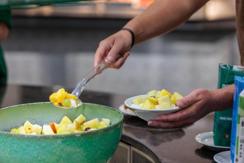 iemand die met een lepel eten in een fruitschaal schept bij Princes Gardens in Londen