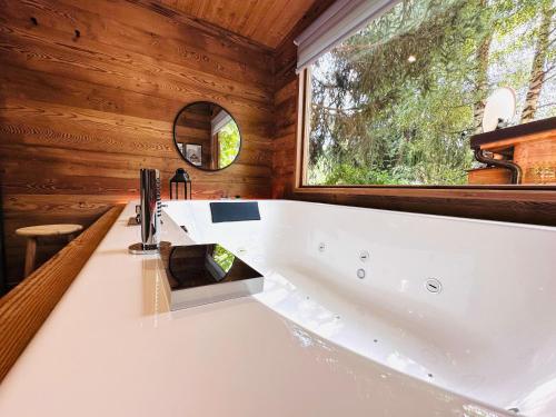 a large white tub in a bathroom with a window at Bijoux Des Alpes - Mont Blanc Village in La Salle
