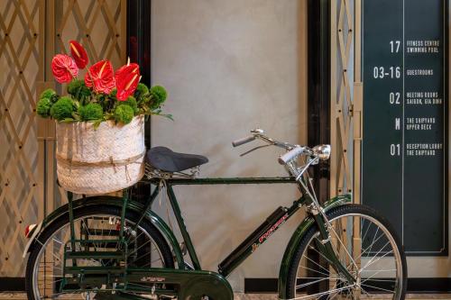 a bike with a basket with red flowers in it at Hotel Indigo Saigon the City by IHG in Ho Chi Minh City