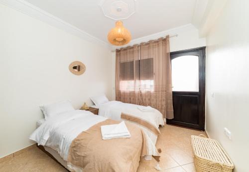 two beds in a room with a window at Appartement Dar Tamraght in Tamraght Ouzdar