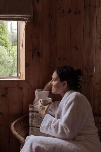 a woman in a bathrobe holding a cup of coffee at Stoep By Ideas Cartel in Kalk Bay