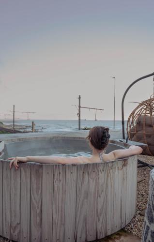 a woman in a hot tub by the ocean at Stoep By Ideas Cartel in Kalk Bay