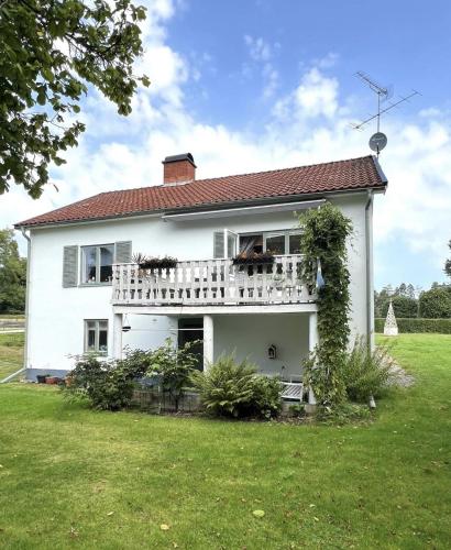 a white house with a balcony and a yard at Renovated Lake view Retreat with Kayaks & Big Garden in Klavreström