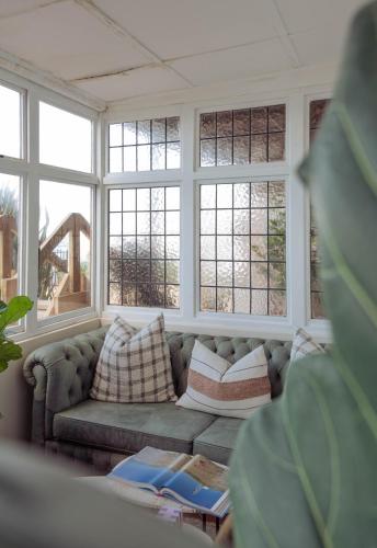 a living room with a couch in front of windows at Stoep By Ideas Cartel in Kalk Bay