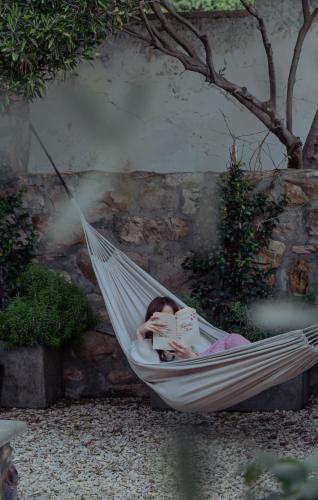 a child laying in a hammock reading a book at Stoep By Ideas Cartel in Kalk Bay