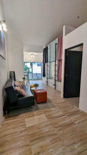 a living room with a black couch and a red stool at Ocean Lovers Taganga - PADI Dive Center & Hostel in Taganga