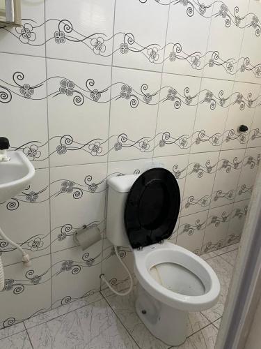 a bathroom with a white toilet with a black lid at Kit net mobiliada in Belém