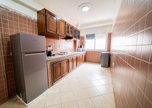 a kitchen with wooden cabinets and a refrigerator at Appartement Dar Tamraght in Tamraght Ouzdar