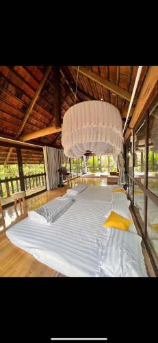 a large white bed in a room with a chandelier at KoMleo Farm in Buôn Kô M'lêo