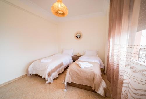 two twin beds in a room with a window at Appartement Dar Tamraght in Tamraght Ouzdar