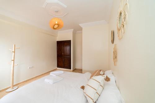 a bedroom with a white bed and a cross on the wall at Appartement Dar Tamraght in Tamraght Ouzdar