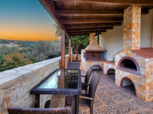 a patio with a table and chairs and an outdoor oven at Agnanti Marina villa with private pool in Skouloúfia