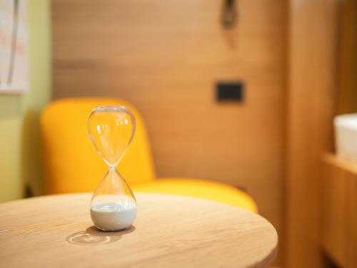 a hourglass sitting on a table with a yellow chair at Boutique Guesthouse - Marina Monfalcone in Monfalcone