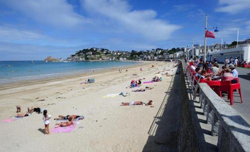 a beach with people laying on the sand and the ocean at Les acacias in Lamballe Armor