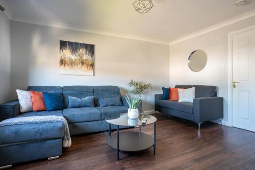 a living room with a blue couch and a table at Mercer Apartment in Alloa